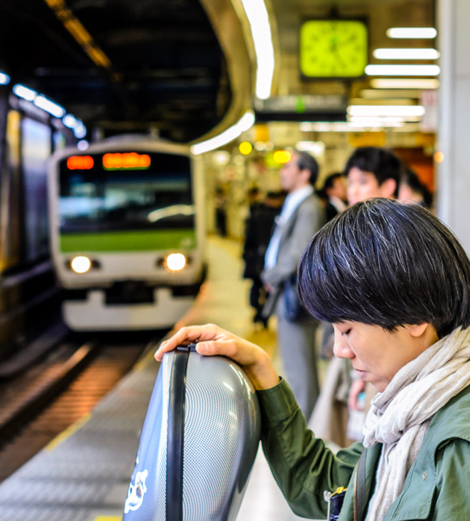 A photograph of a girl waiting for the Yamanote line train at a station in Tokyo.